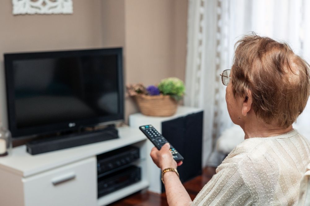 Person Holding A Remote, Watching A TV In A Living Room — MATV Systems Australia Pty Ltd in Wickham, NSW