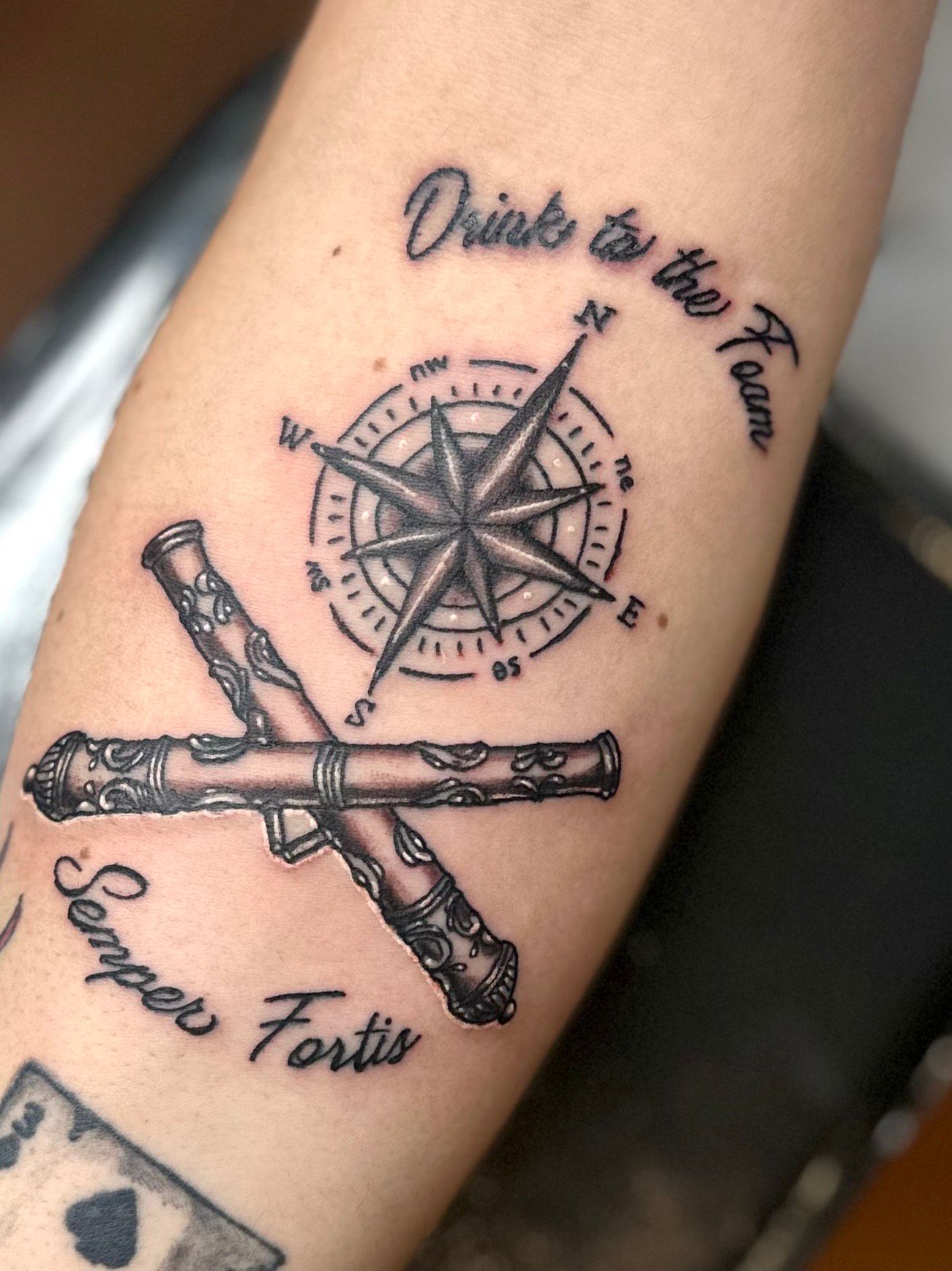 Tattoo on arm: compass rose, crossed cannons,