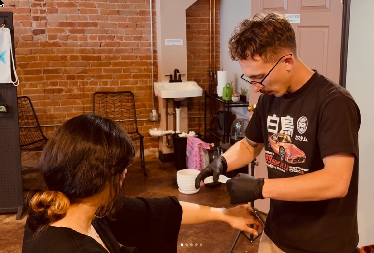 Tattoo artist giving a tattoo at a convention, with two assistants and a partially visible client.