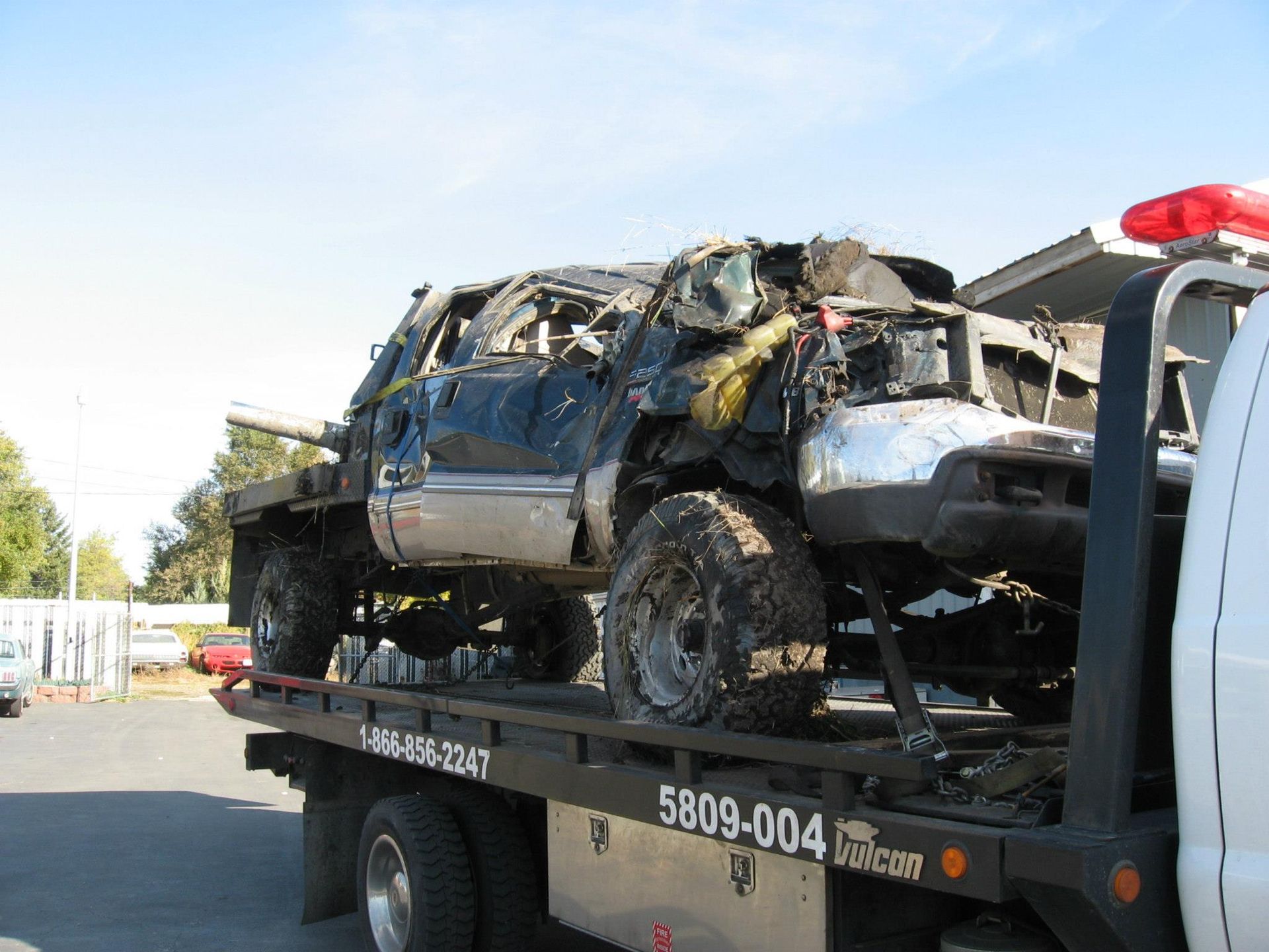 A wrecked truck is being towed by a tow truck