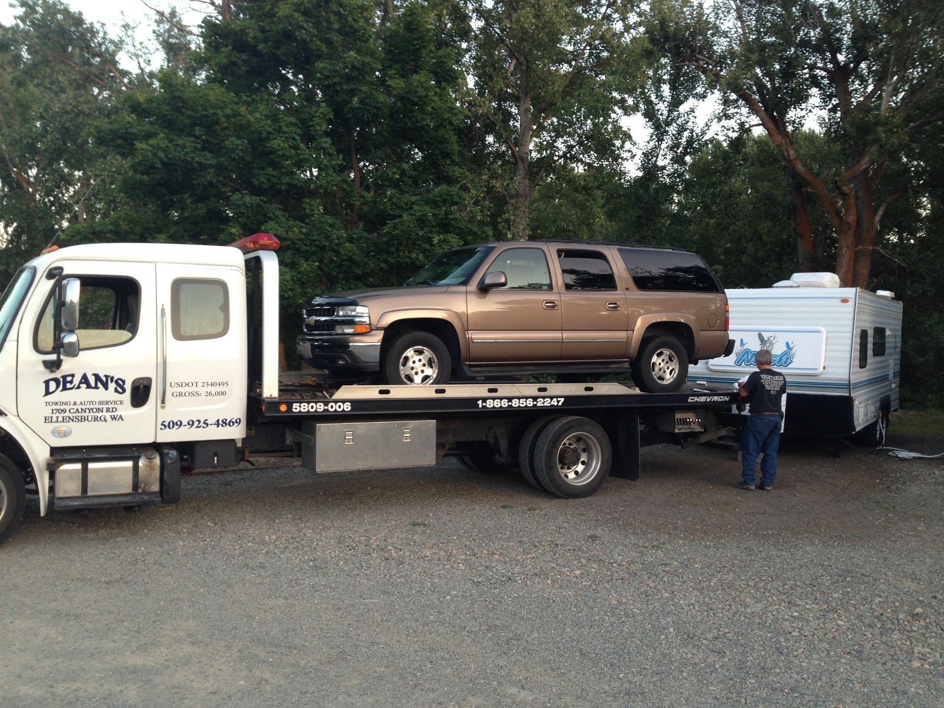 A dean 's tow truck is carrying a suv and a trailer