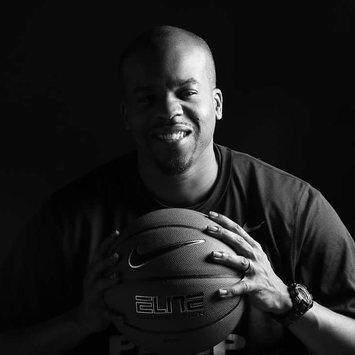 A man is holding a nike elite basketball in his hands.
