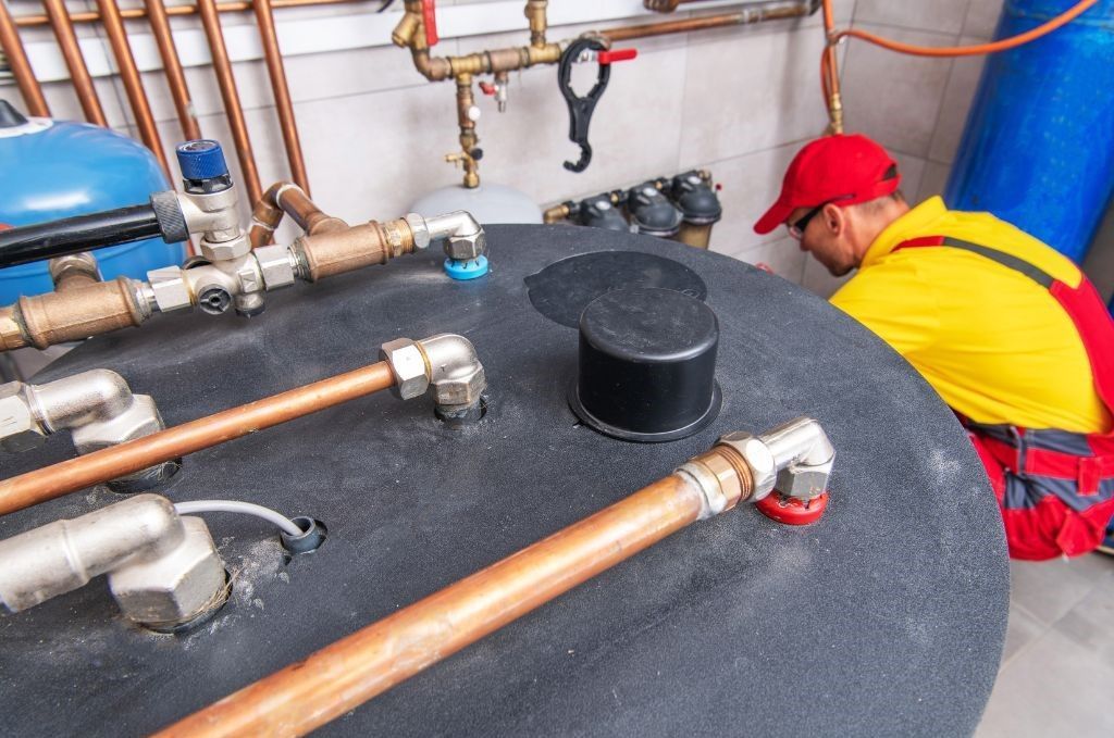 A man is working on a water heater in a basement