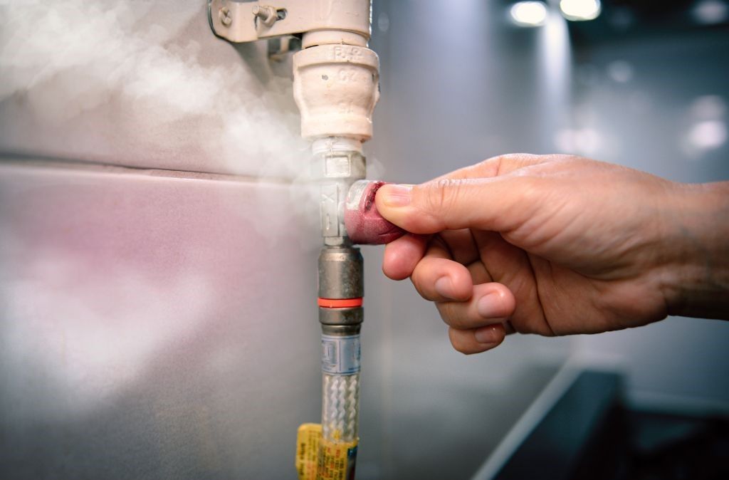 A person is holding a pipe with steam coming out of it.
