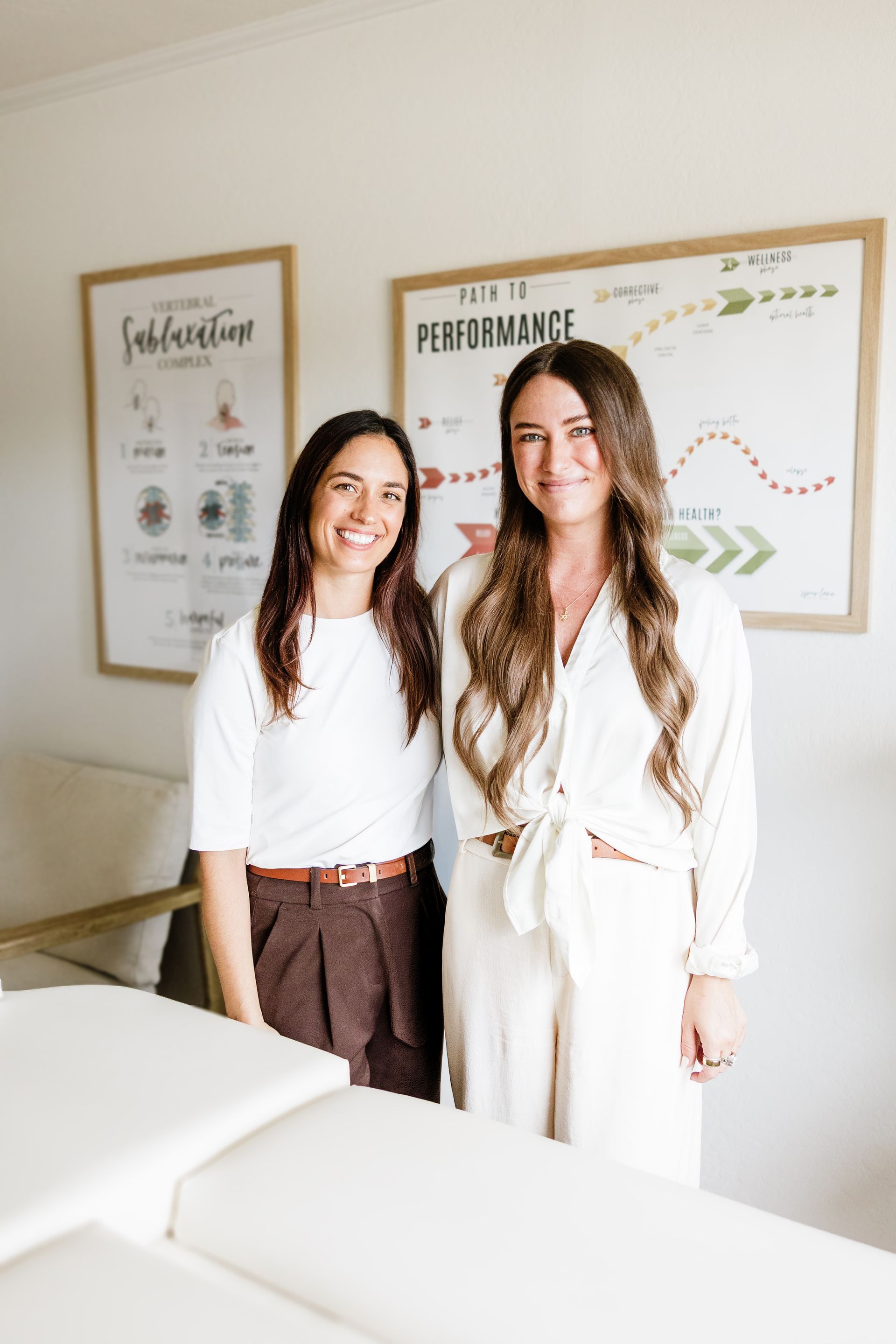 Dr. Chloé and Dr. Julie smiling next to an adjustment table.