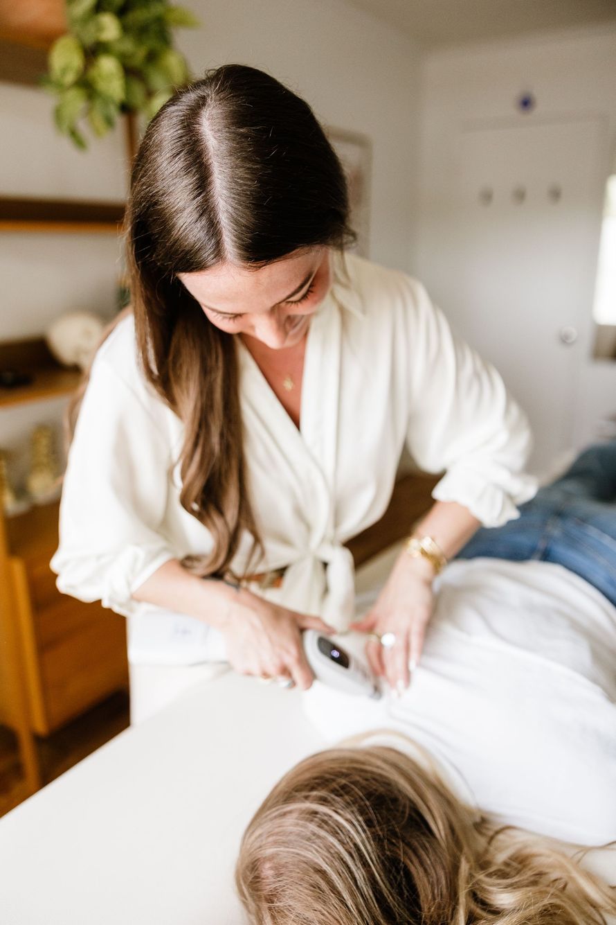 Chiropractor holding a handheld device called an Activator over a patient's back, demonstrating a chiropractic treatment.