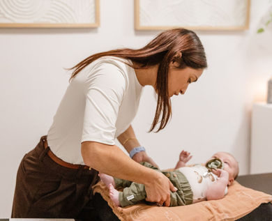 Woman adjusts baby on changing table in a bright room