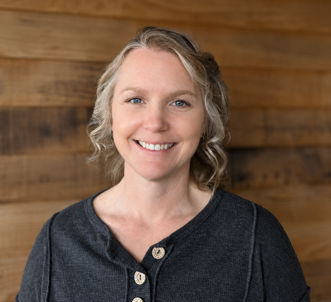 Smiling woman in a dark top against a blurred wooden background