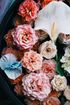 Assorted pastel flowers and a white calla lily arranged in a dark bowl