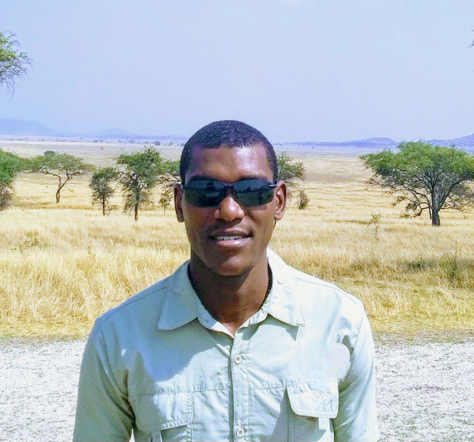 Stan Safari guide, smiling outdoors against a dry, savanna-like background.