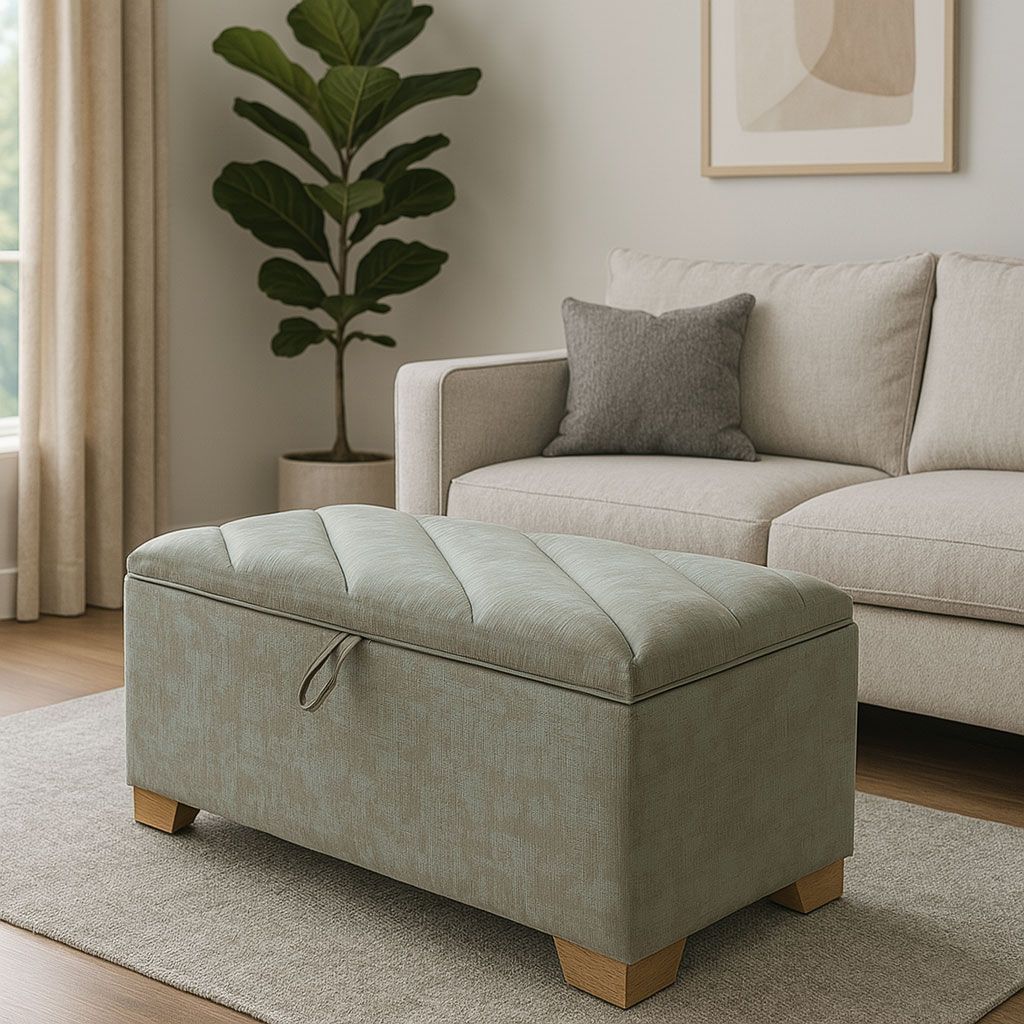 Otomana capitoné gris claro en una sala de estar beige junto a un sofá y una planta en maceta.