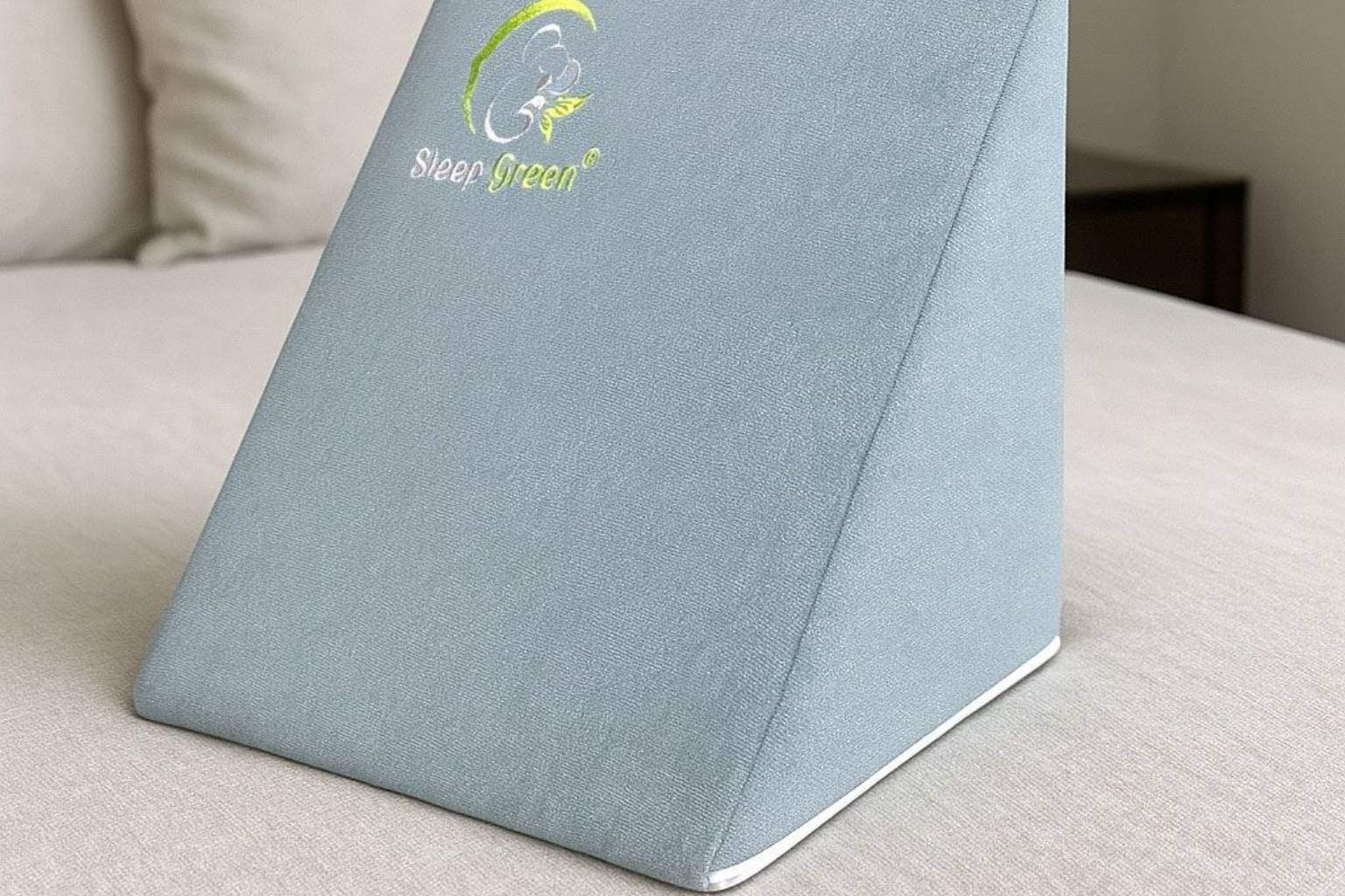 Tarjeta de mesa triangular gris con logotipo y texto verdes sobre un sofá beige.