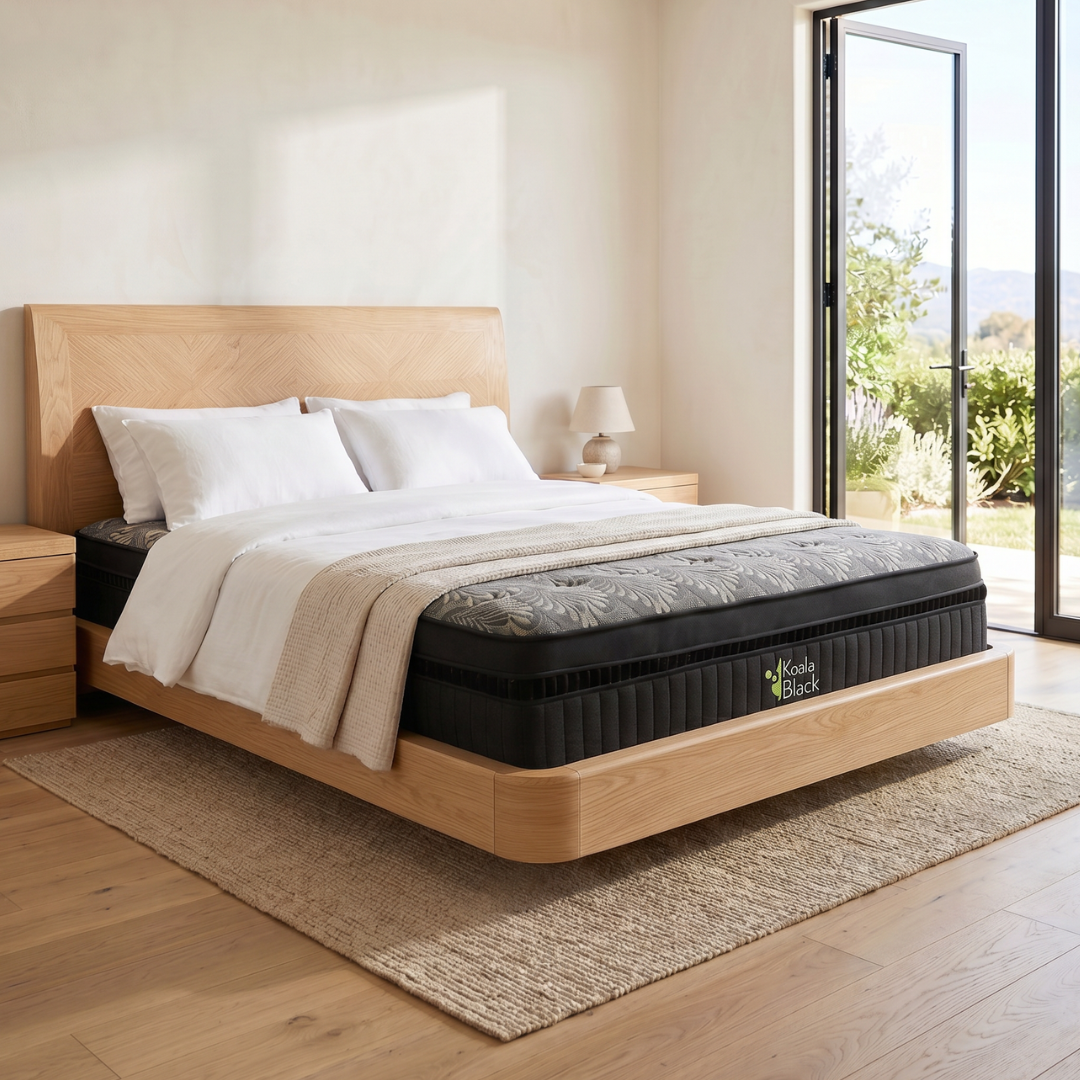Dormitorio minimalista con cama de madera, ropa de cama blanca, alfombra tejida y puerta de cristal abierta con vistas a un jardín.