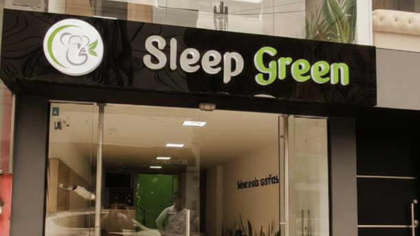 Fachada de la tienda Sleep Green con letrero negro, letras verdes y un logotipo circular sobre la entrada.