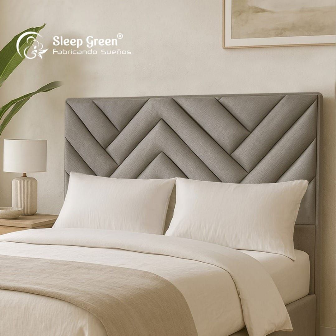 Cabecero gris con capitoné en forma de espiga sobre una cama beige impecablemente hecha en un dormitorio suave y moderno.