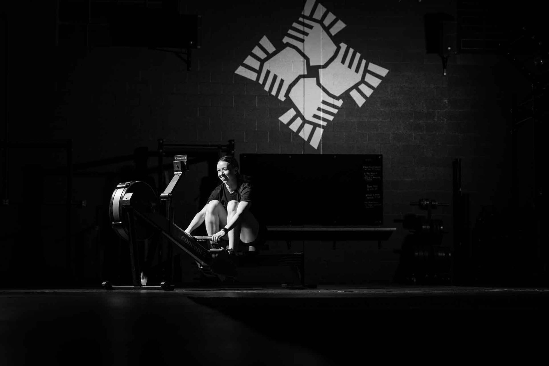 Black-and-white stage photo of a woman on a rowing machine at the sect in south salt lake