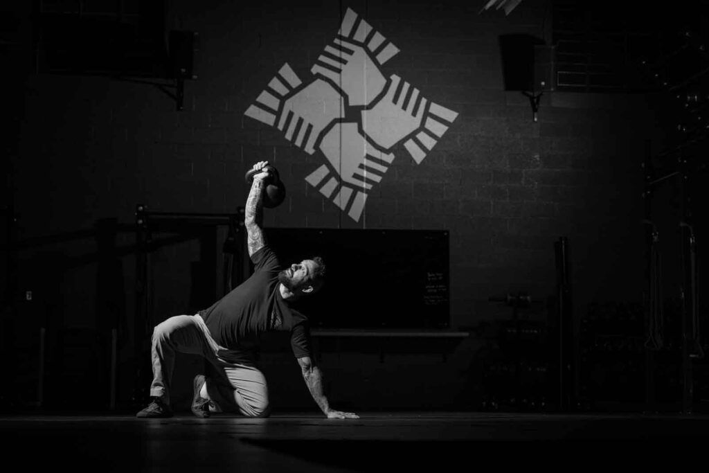 Person in a black-and-white dance pose on a stage beneath a geometric wall logo