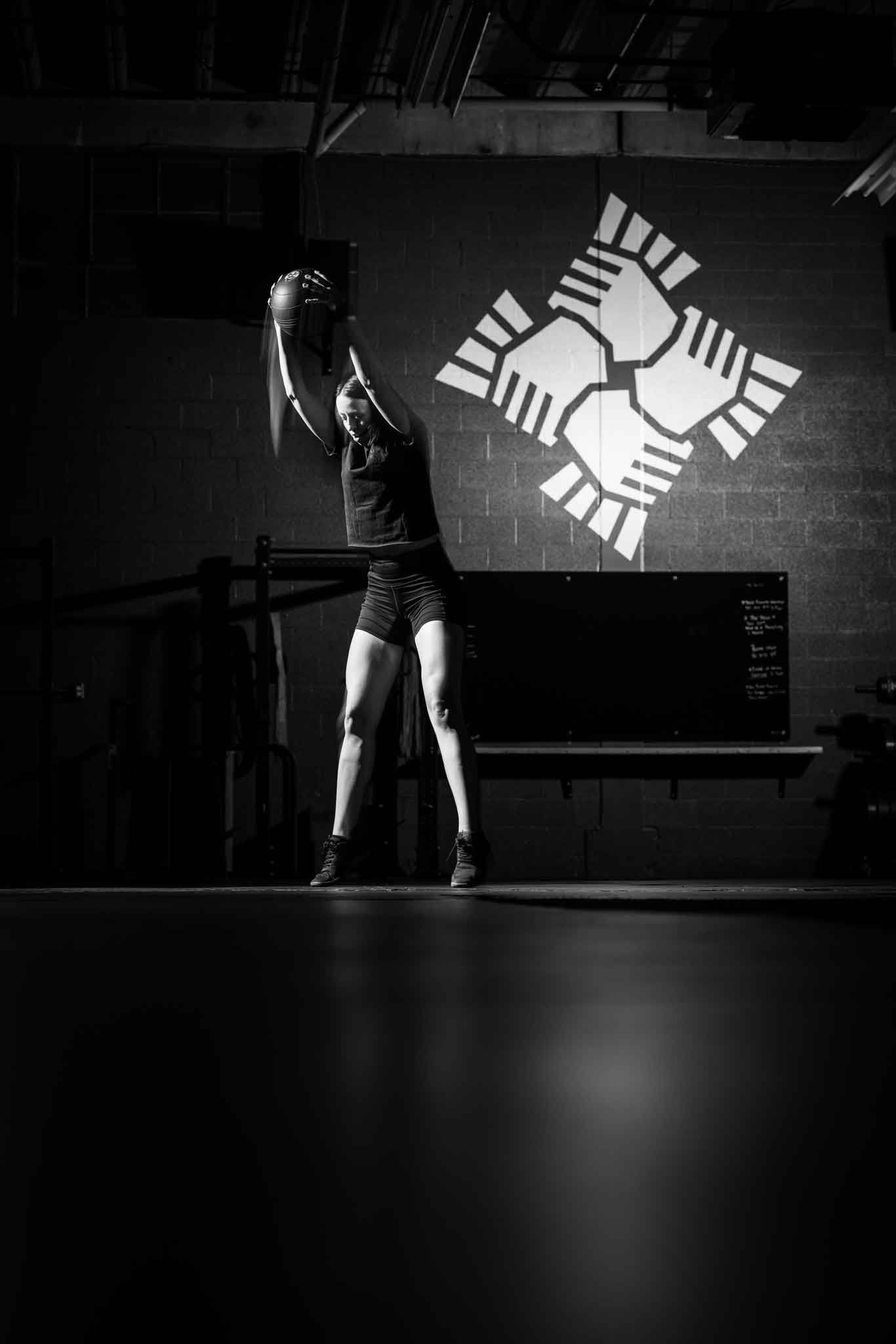 Black-and-white stage scene with a dancer posing beneath a geometric wall light pattern.