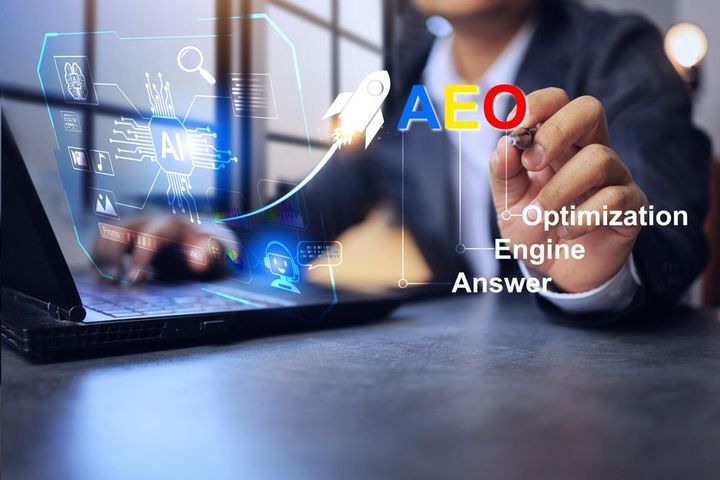 Person typing on laptop beside “AEO” and “Optimization Engine Answer” text, blue digital interface.