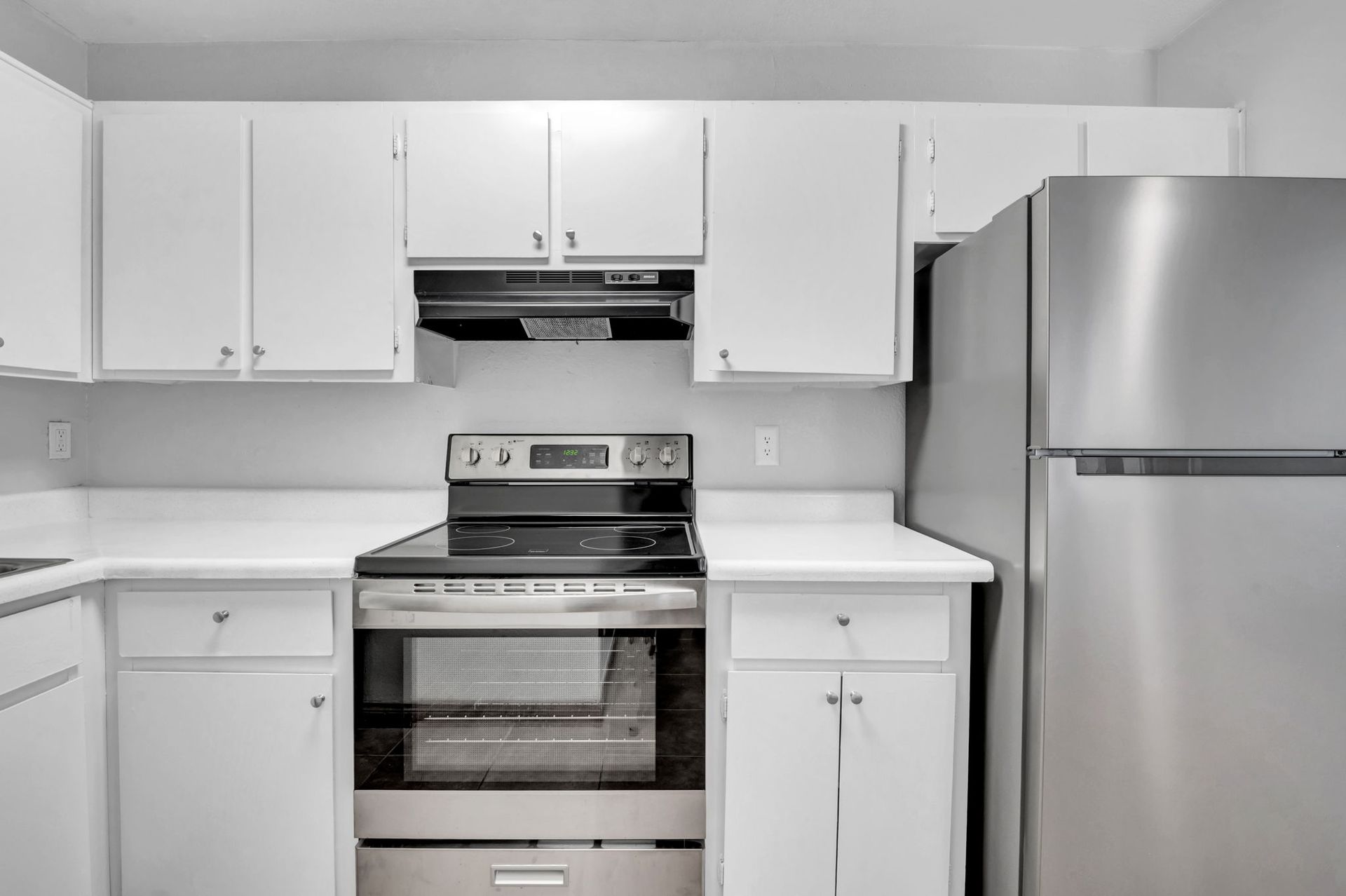 Image of a kitchen with white cabinets, and stainless steel appliances with silver hardware.