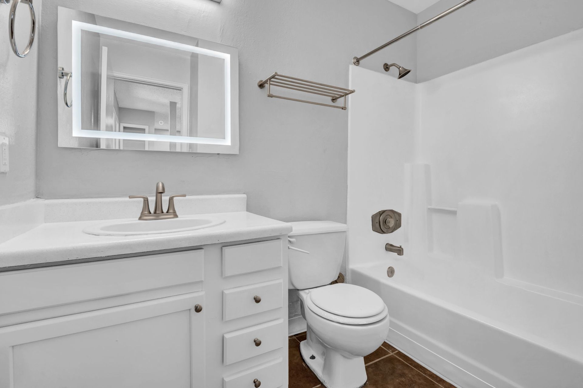 A reno bathroom with white cabinetry, new hardware, a mirror with built in modern designer lighting, and lux countertops. 