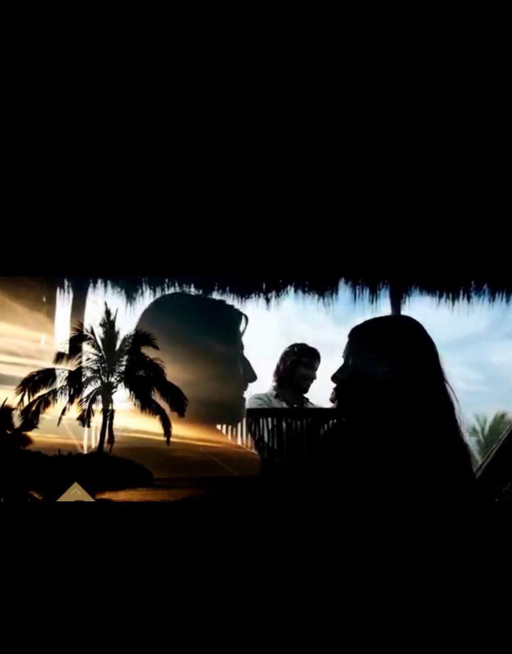 Pareja silueteada con una escena de atardecer tropical reflejada en su contorno.