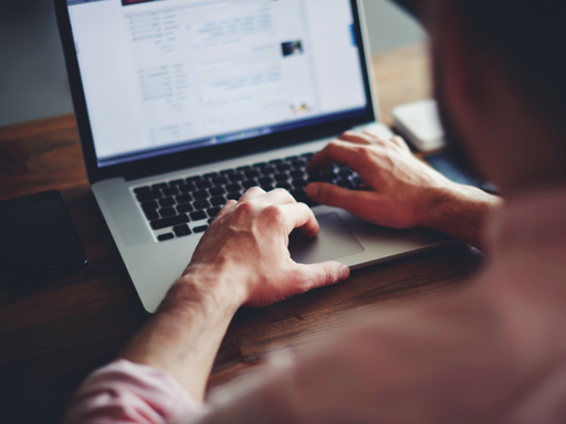 A man is typing on a laptop computer with his hands on the keyboard