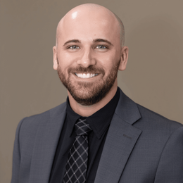 A man with a beard is wearing a suit and tie.