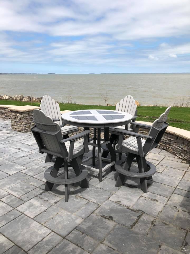 Patio table and chairs on a stone terrace overlooking open water under a cloudy sky