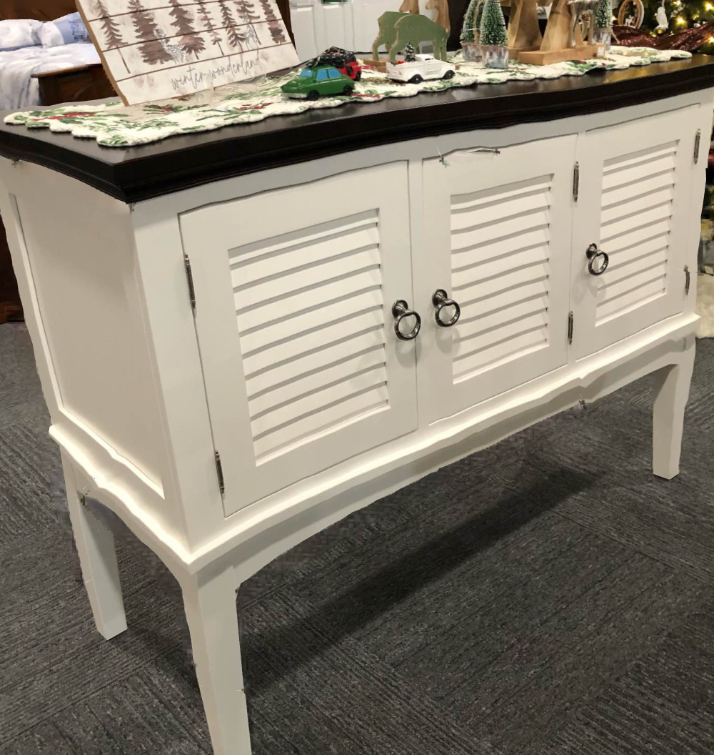 White louvered sideboard cabinet with black top on a carpeted floor
