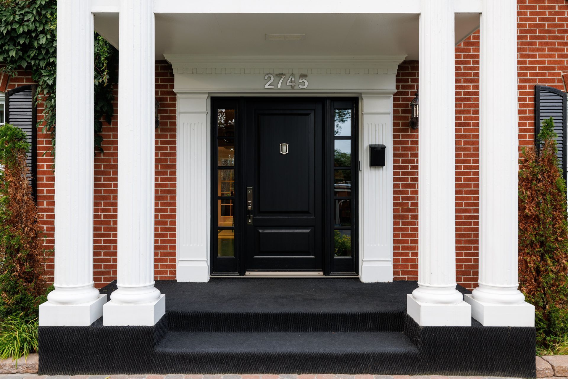 A brick house with a black door and white columns
