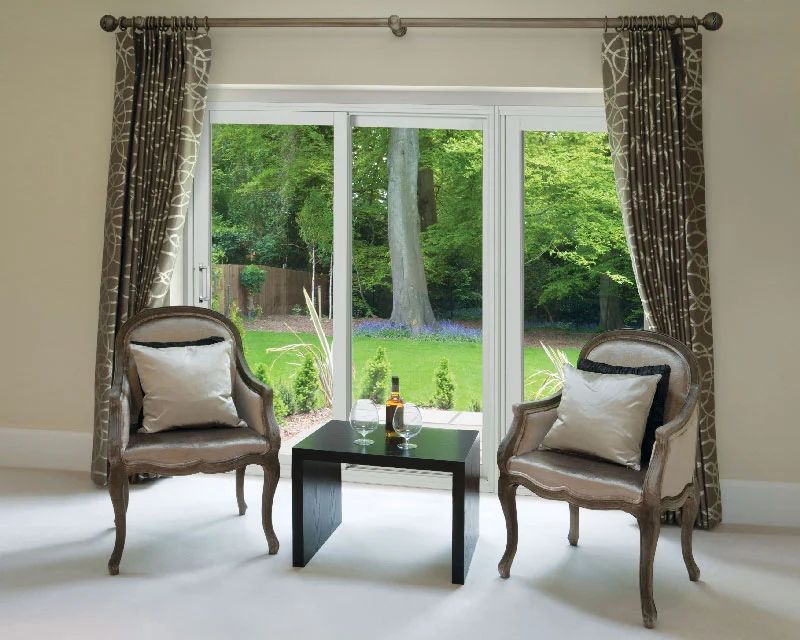 A living room with two chairs and a table with a bottle of wine on it.