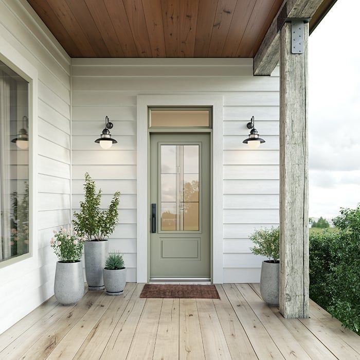 A porch with a green door and potted plants
