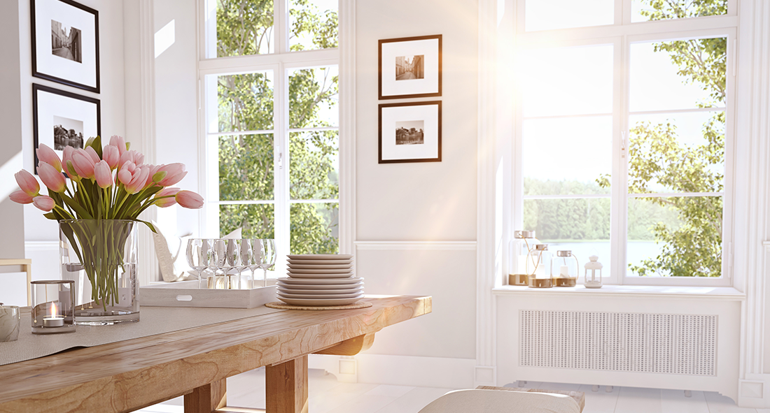 A dining room with a wooden table and a vase of flowers on it.