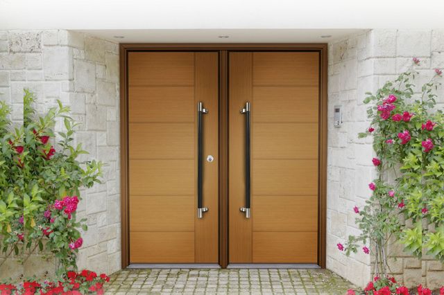 A pair of wooden doors with black handles on a brick wall.