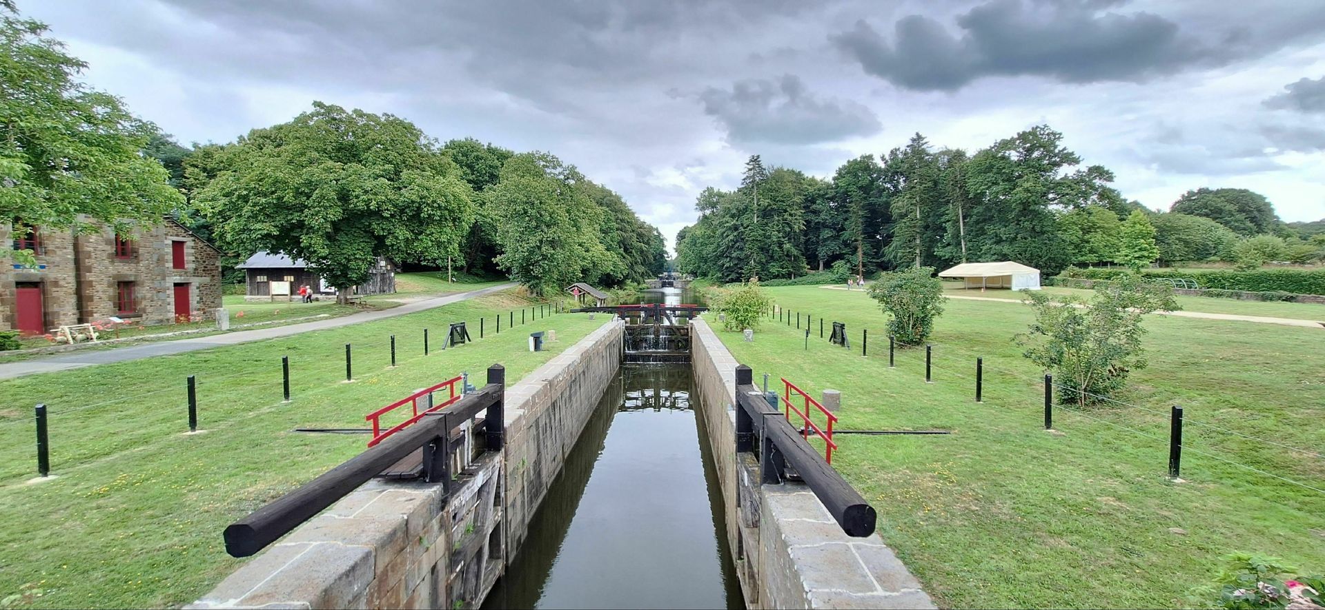 Un canal étroit entouré d'herbe et d'arbres par temps nuageux