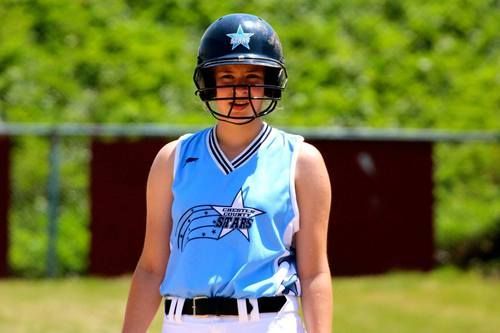 Softball player in a blue jersey and black helmet standing on a field.