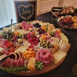 Large charcuterie board with fruit, cheese, crackers, and a chalkboard sign reading “love”