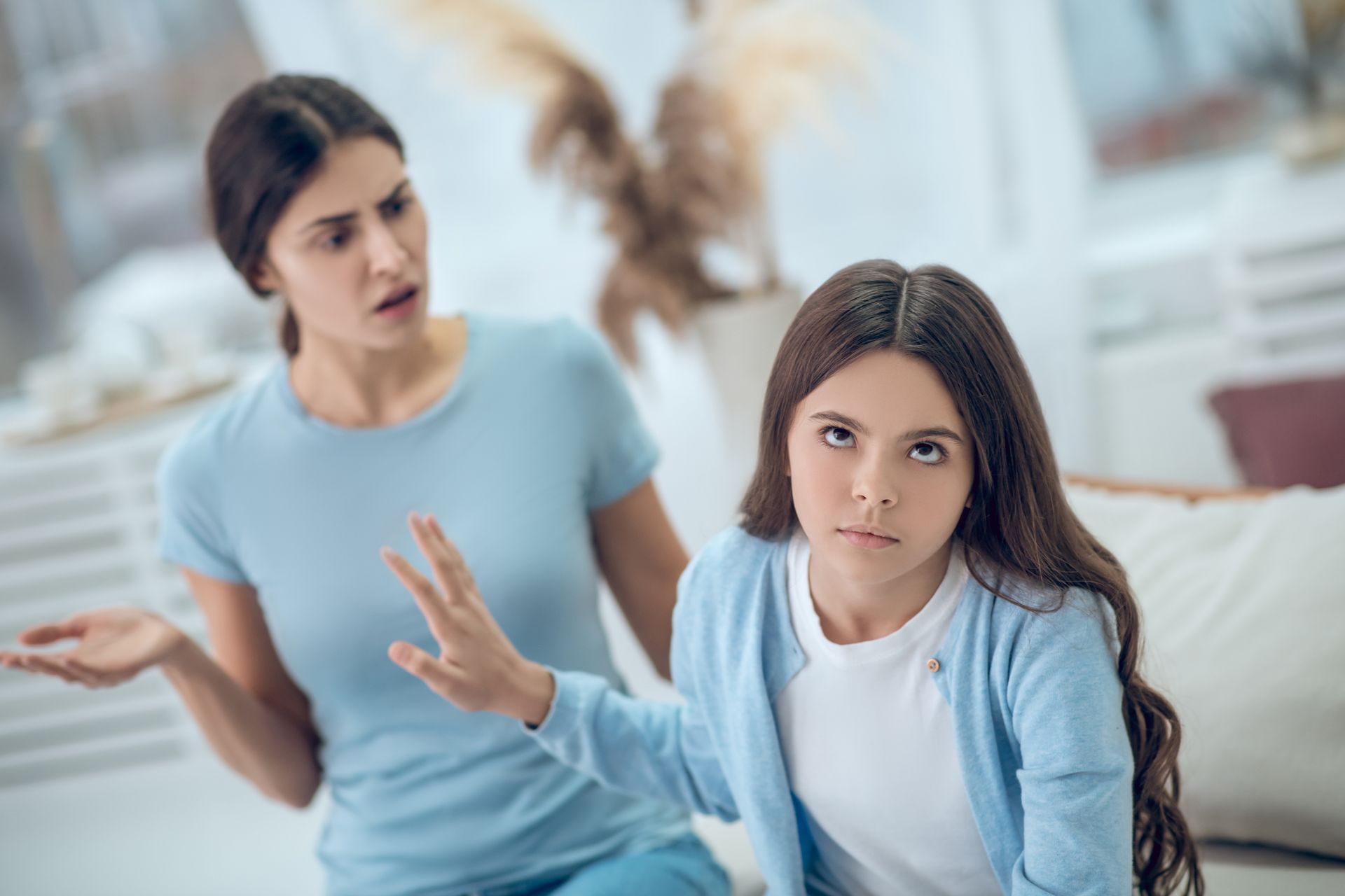 Woman gesturing angrily at a teen girl, who has a defiant expression and is pushing back with her hand.
