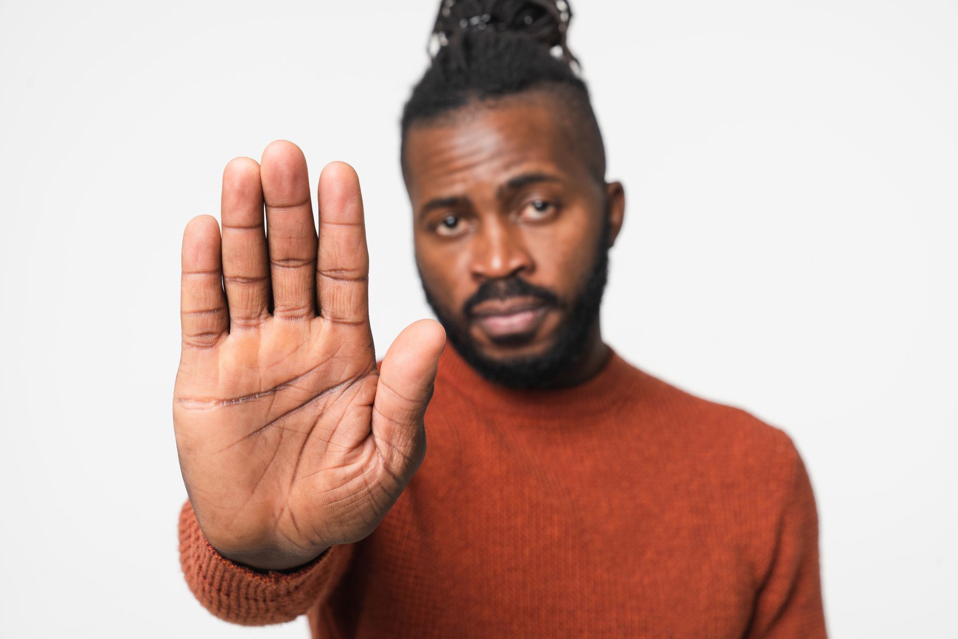 Man holding out his hand in a stop gesture, looking directly at the viewer.