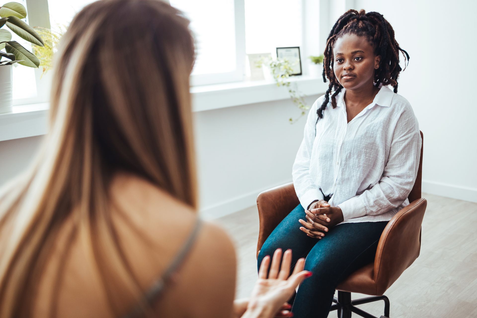 Woman in therapy session, sitting and listening attentively, in an office setting.