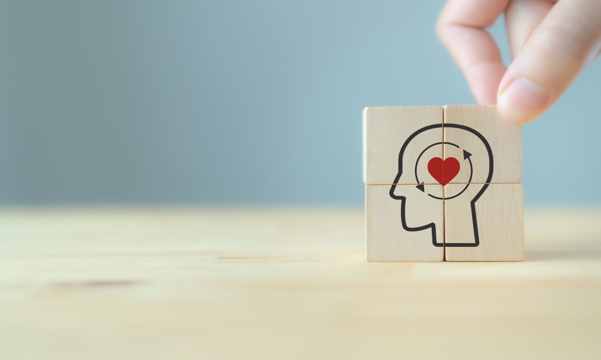 Hand rotating wooden block with head and heart symbol.