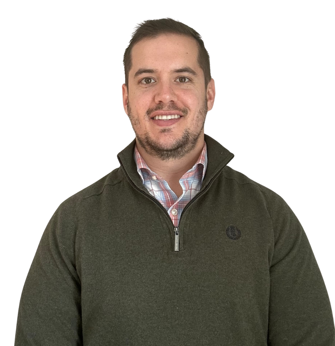 Man smiling, wearing a green sweater with zipper and patterned shirt. White background.