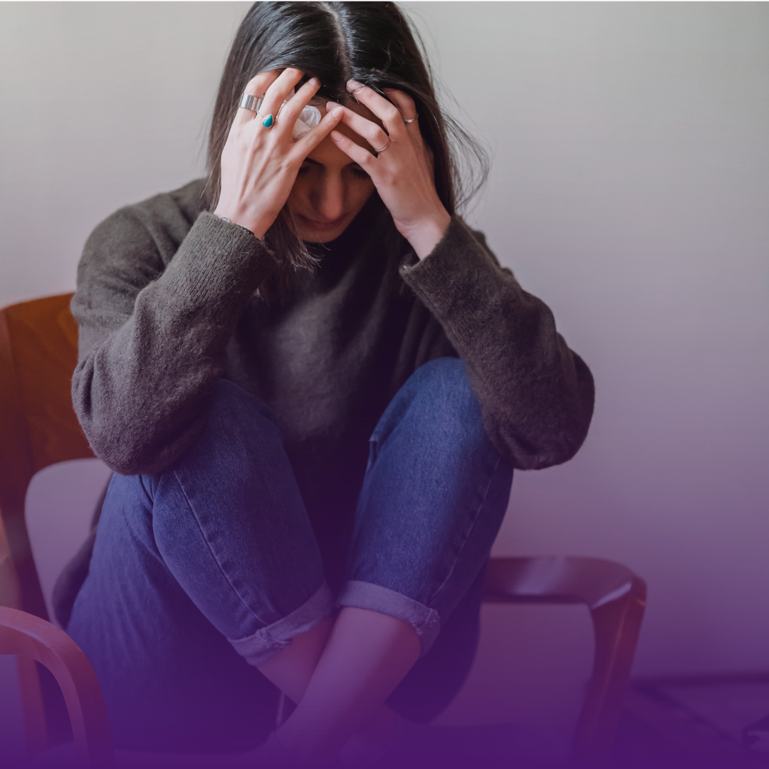 Person with head in hands, slumped in a chair, expressing distress.