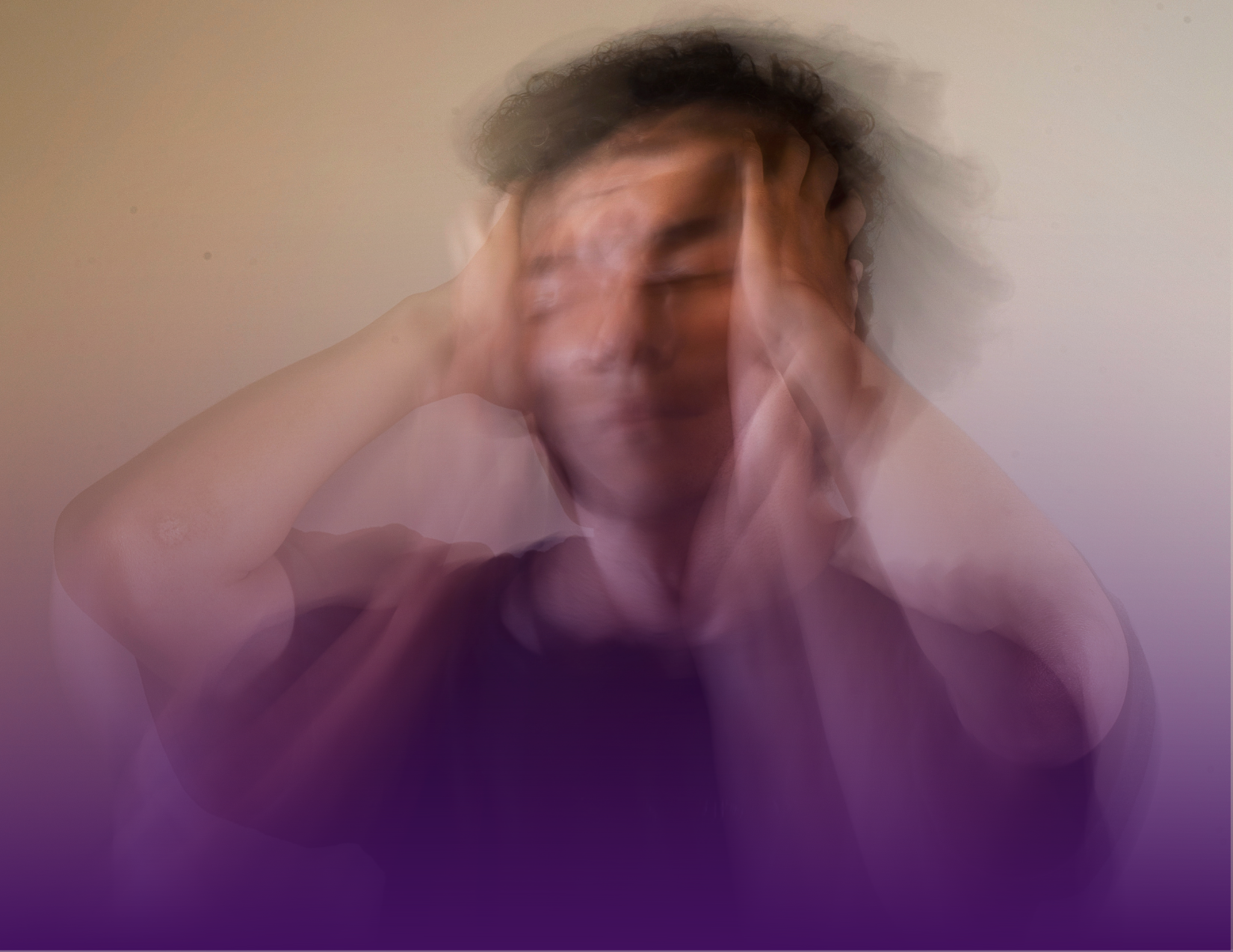 Person holding head, blurred motion, eyes closed, appearing stressed against a gradient purple background.