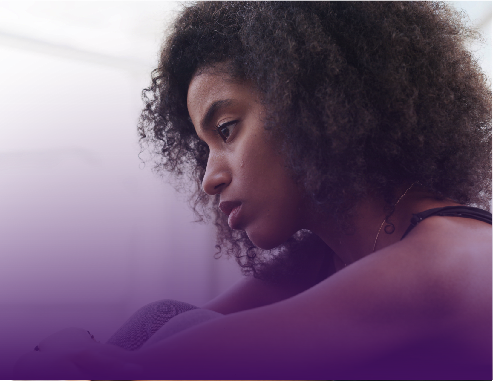 A person with curly hair, in a thoughtful pose with a purple gradient background.