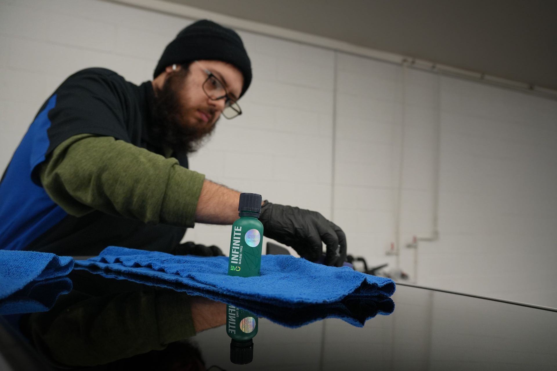 A man is cleaning a car with a sponge in a garage.