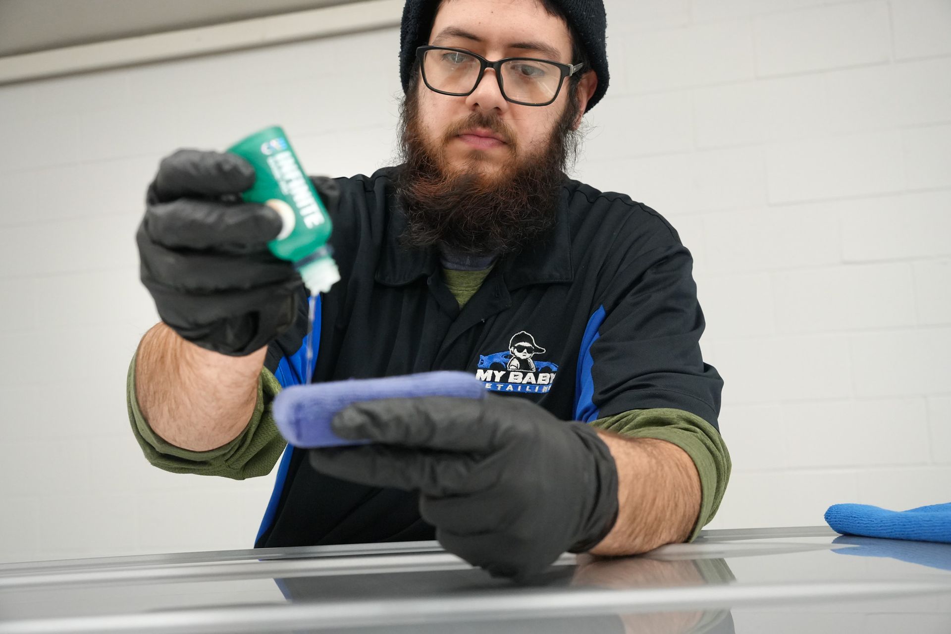 A man is cleaning a car with a sponge next to a bottle of ion.
