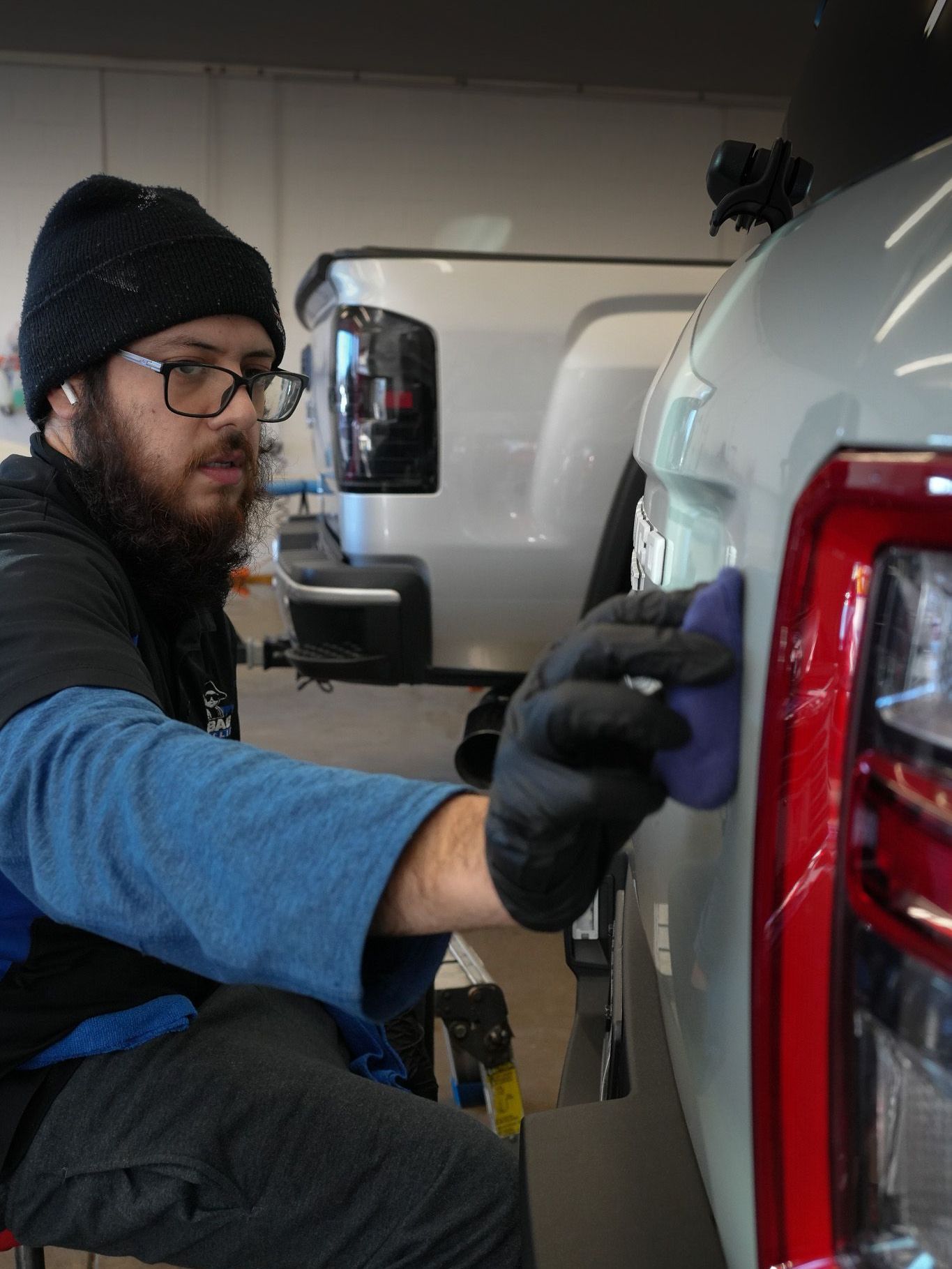 A man is cleaning a car with a sponge next to a bottle of ion.