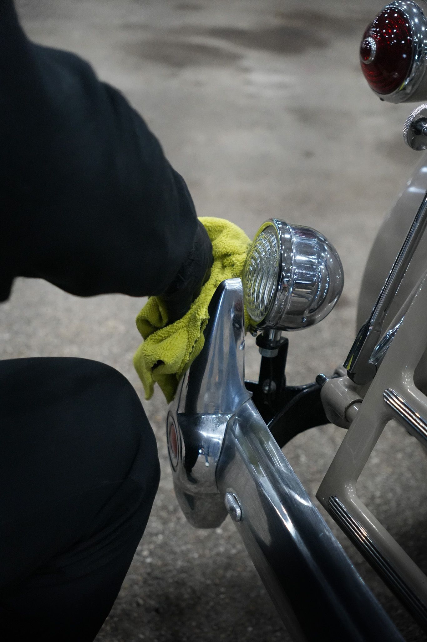 A person is cleaning a car with a yellow cloth.